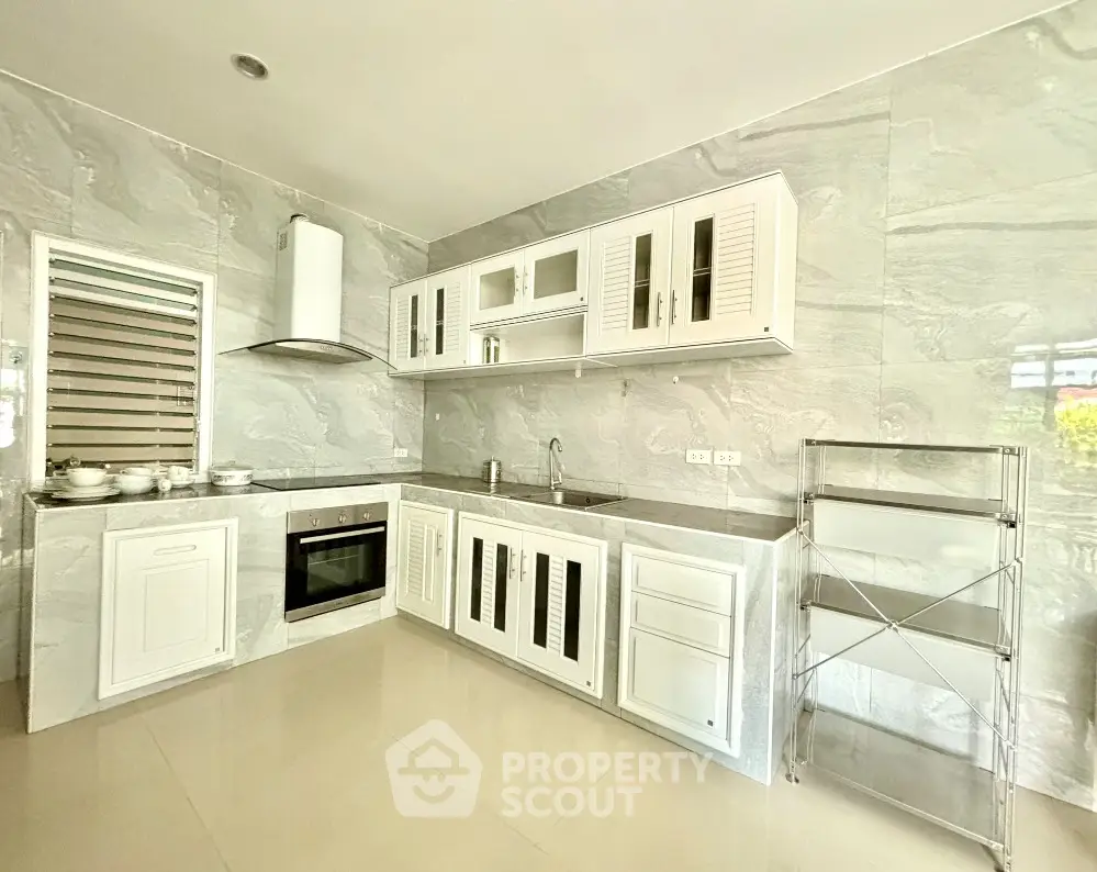 Modern kitchen with sleek white cabinetry and built-in oven in a bright, spacious layout.