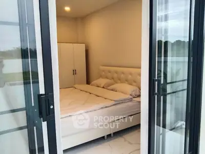 Modern bedroom with glass doors and elegant white decor in a stylish apartment.