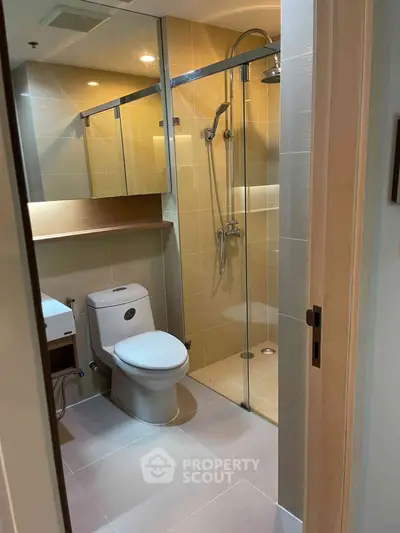 Modern bathroom with glass shower and sleek fixtures in contemporary apartment.