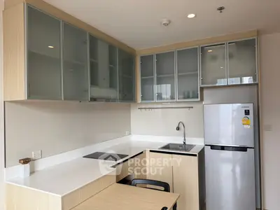 Modern kitchen with sleek cabinets and stainless steel fridge in a cozy apartment
