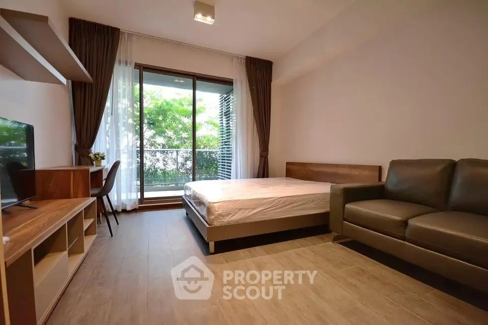Modern studio apartment with cozy living area and garden view balcony.