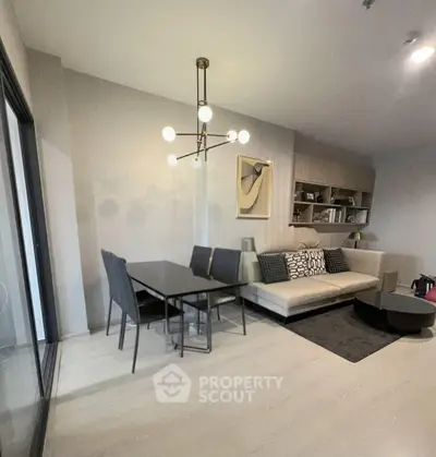 Modern living room with stylish decor and dining area, featuring contemporary lighting and sleek furniture.