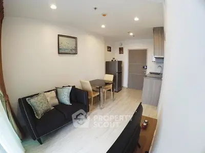 Modern living room with cozy seating and compact dining area in open layout apartment.