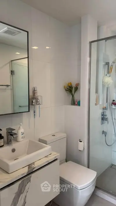 Modern bathroom with glass shower, sleek vanity, and elegant decor