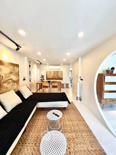 Stylish modern living room with black sofa, woven rug, and elegant decor