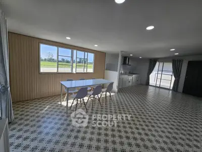Spacious open-plan living area with modern kitchen and dining space, featuring large windows and stylish flooring.