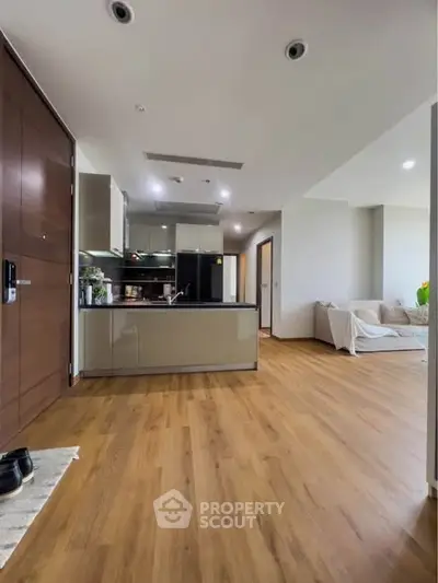 Modern open-layout kitchen and living room with wooden flooring and sleek design.
