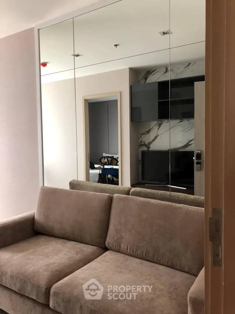 Modern living room with plush sofa and mirrored wall, enhancing space and elegance.