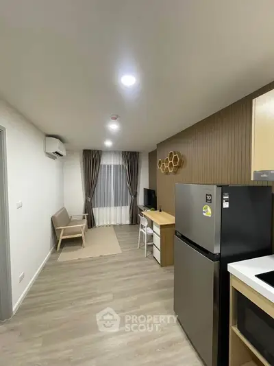 Modern living room with stylish decor and open kitchen layout, featuring sleek appliances and cozy seating area.