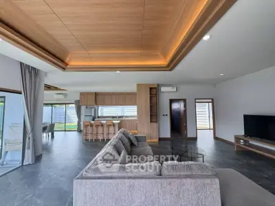 Spacious modern living room with open kitchen and stylish wooden ceiling design.