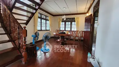 Charming wooden interior with elegant staircase and dining area, featuring classic decor and natural light.