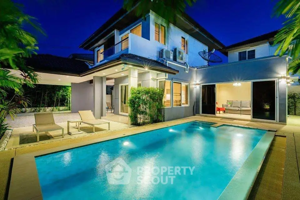Luxurious modern home with a stunning illuminated pool and spacious patio, perfect for evening relaxation.