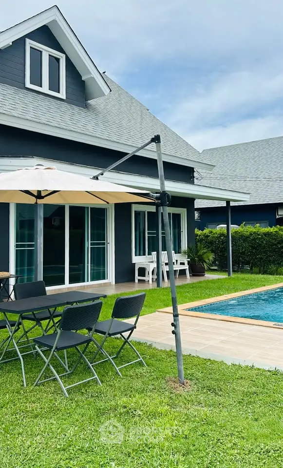 Charming suburban home with poolside patio and lush green lawn, perfect for outdoor relaxation.