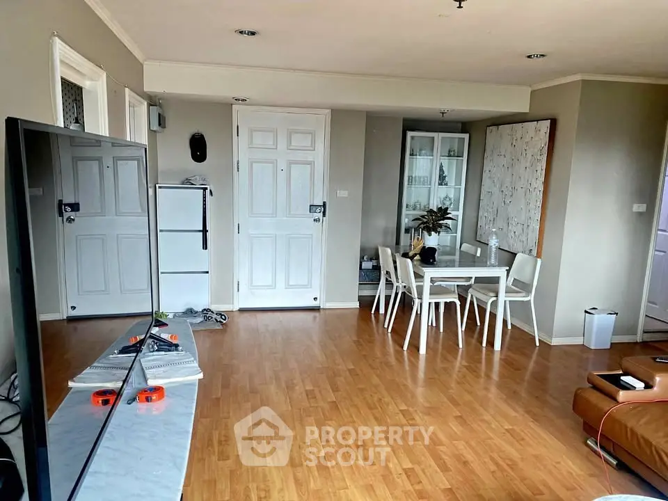 Spacious living room with modern decor and dining area, featuring wooden flooring and ample natural light.