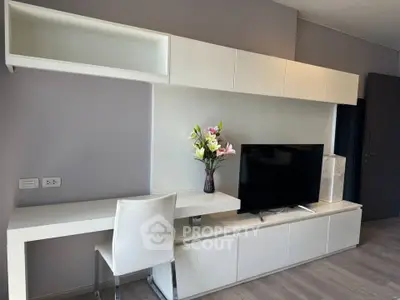 Modern living room with sleek white furniture and flat-screen TV