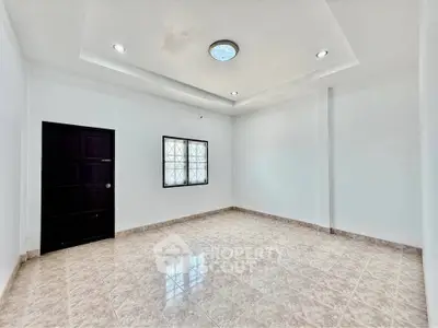 Spacious empty room with tiled flooring and modern ceiling lights, perfect for customization.