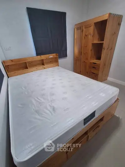 Cozy bedroom with wooden furniture and comfortable mattress, perfect for restful nights.