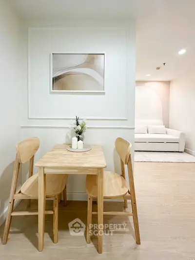 Chic dining area with wooden table and chairs, modern art, and cozy living room in a stylish apartment.