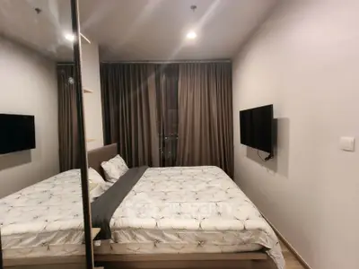 Modern bedroom with cozy bedding and wall-mounted TV in a stylish apartment.