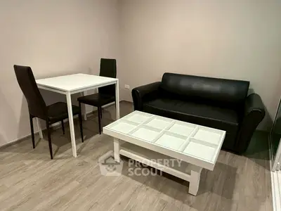 Modern living room with sleek black sofa, white coffee table, and dining set on wooden flooring.