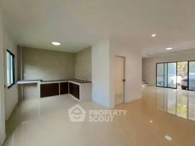 Spacious open-plan living area with modern kitchen and large windows.