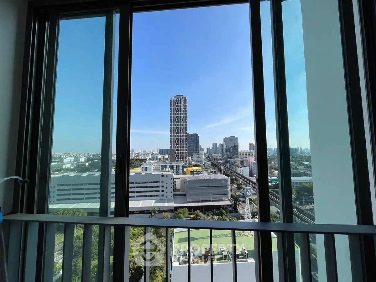 Stunning cityscape view from high-rise balcony with clear blue sky.