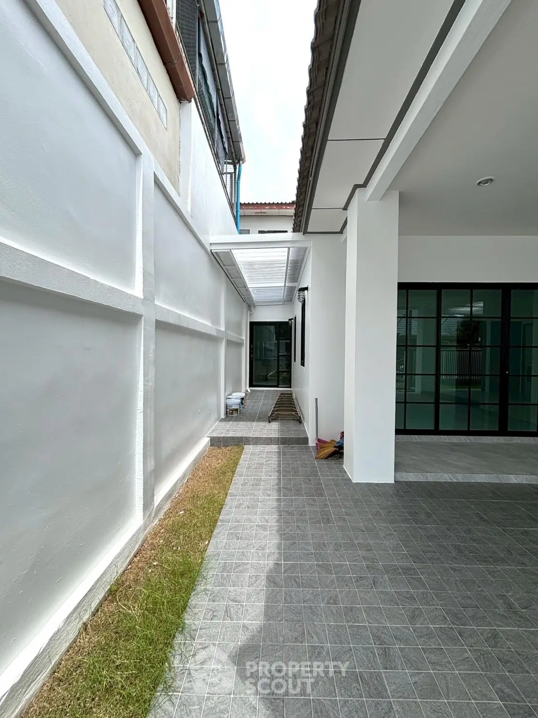 Modern exterior walkway with tiled flooring and sleek white walls in a contemporary property.