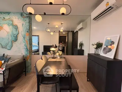 Modern living room with stylish decor, featuring a dining area, wall art, and contemporary lighting.