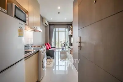 Modern apartment interior with open kitchen and living area, featuring sleek appliances and a bright view.