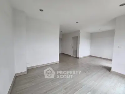 Spacious empty room with modern flooring and recessed lighting, ideal for customization.