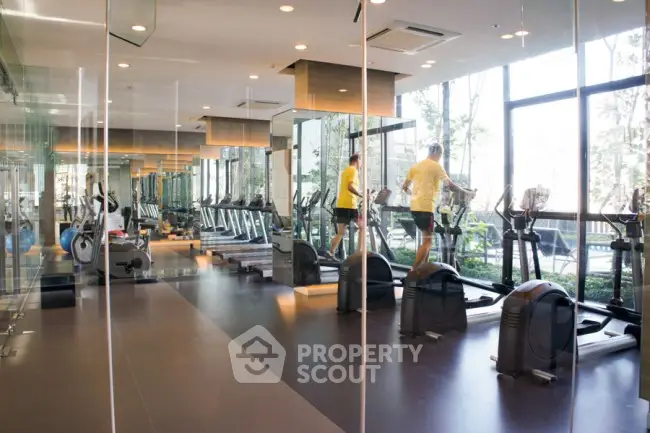 Modern gym with large windows and state-of-the-art exercise equipment in a luxury residential complex.
