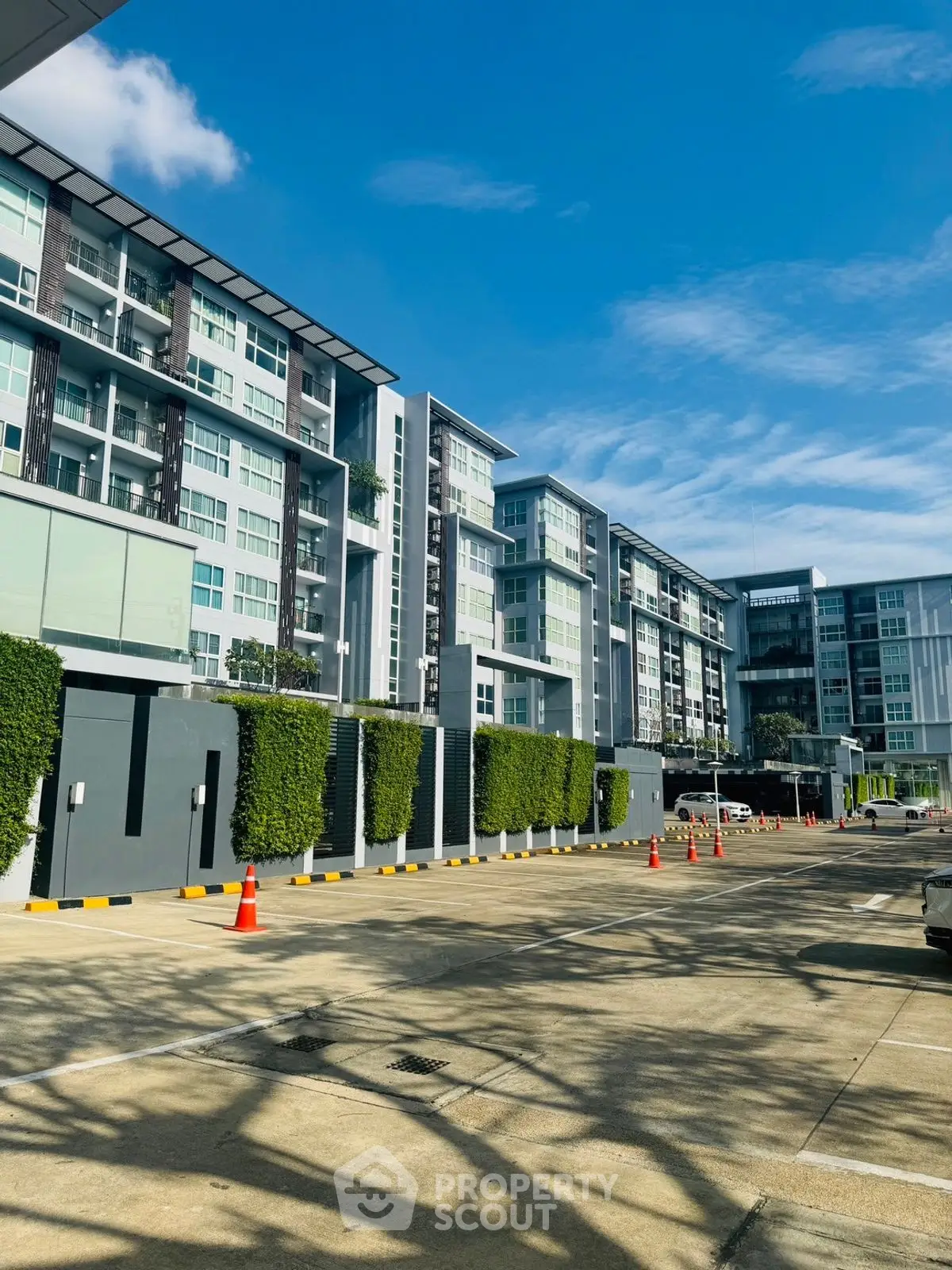 Modern residential building with spacious parking area under clear blue sky.