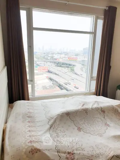 Cozy bedroom with large window offering stunning city view