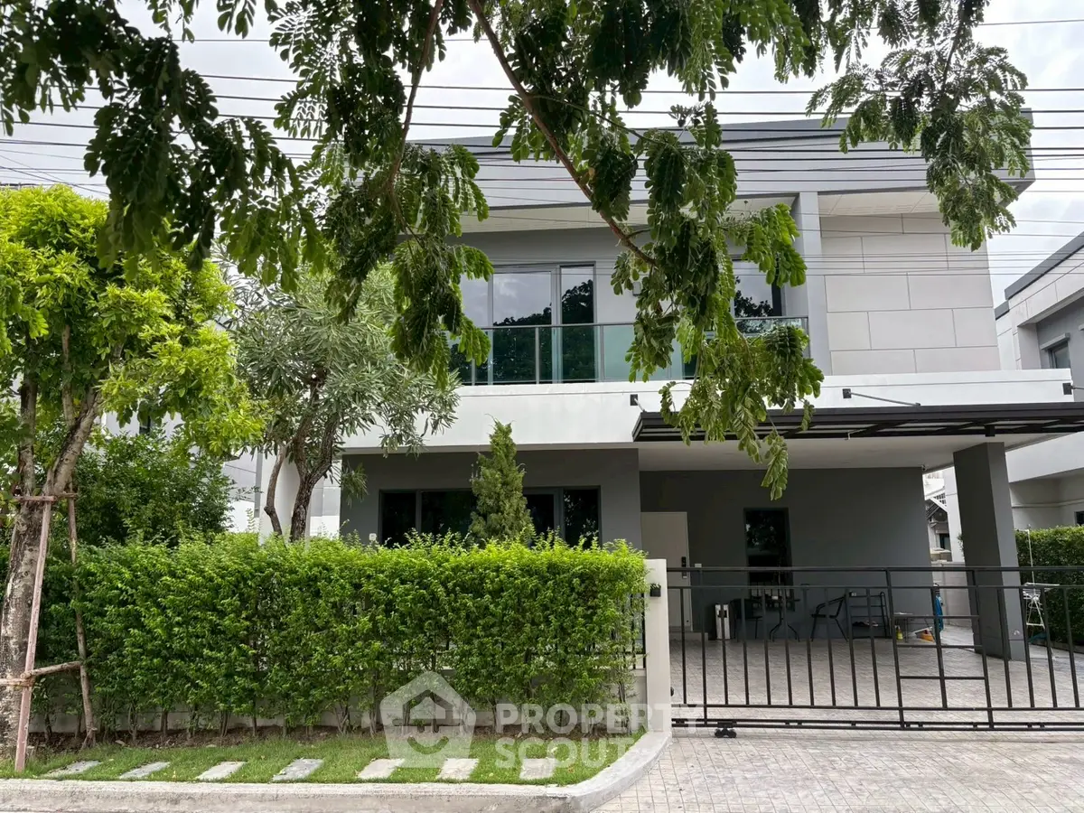 Modern two-story house with sleek design and lush greenery in a serene neighborhood.
