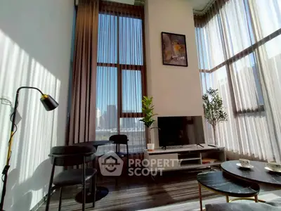 Modern living room with high ceilings, large windows, and stylish decor in a luxury apartment.