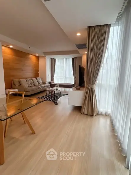 Spacious modern living room with wooden flooring and large windows for natural light.