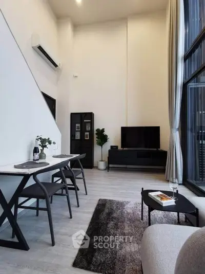 Modern living room with high ceilings, stylish furniture, and large windows for natural light.