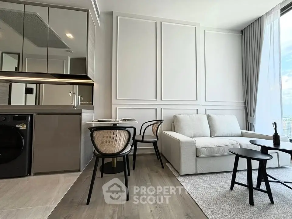Modern living room with sleek kitchen, stylish furniture, and large windows offering a bright and airy atmosphere.