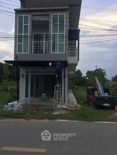 Modern two-story house with large windows and balcony under construction