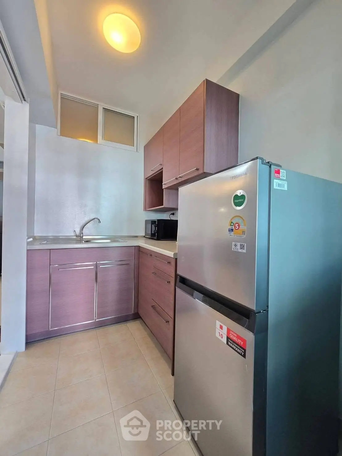 Modern kitchen with sleek cabinetry and stainless steel fridge in a compact layout.