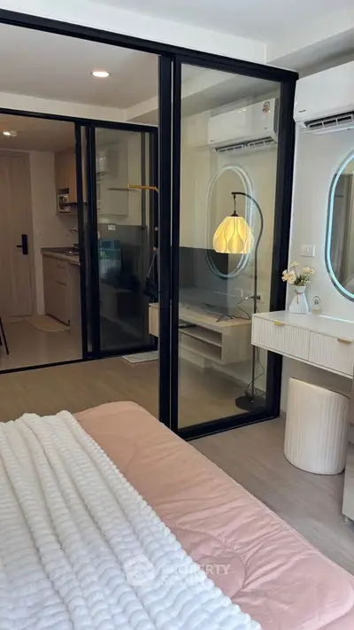 Modern bedroom with glass partition, cozy decor, and view into a stylish kitchen area.