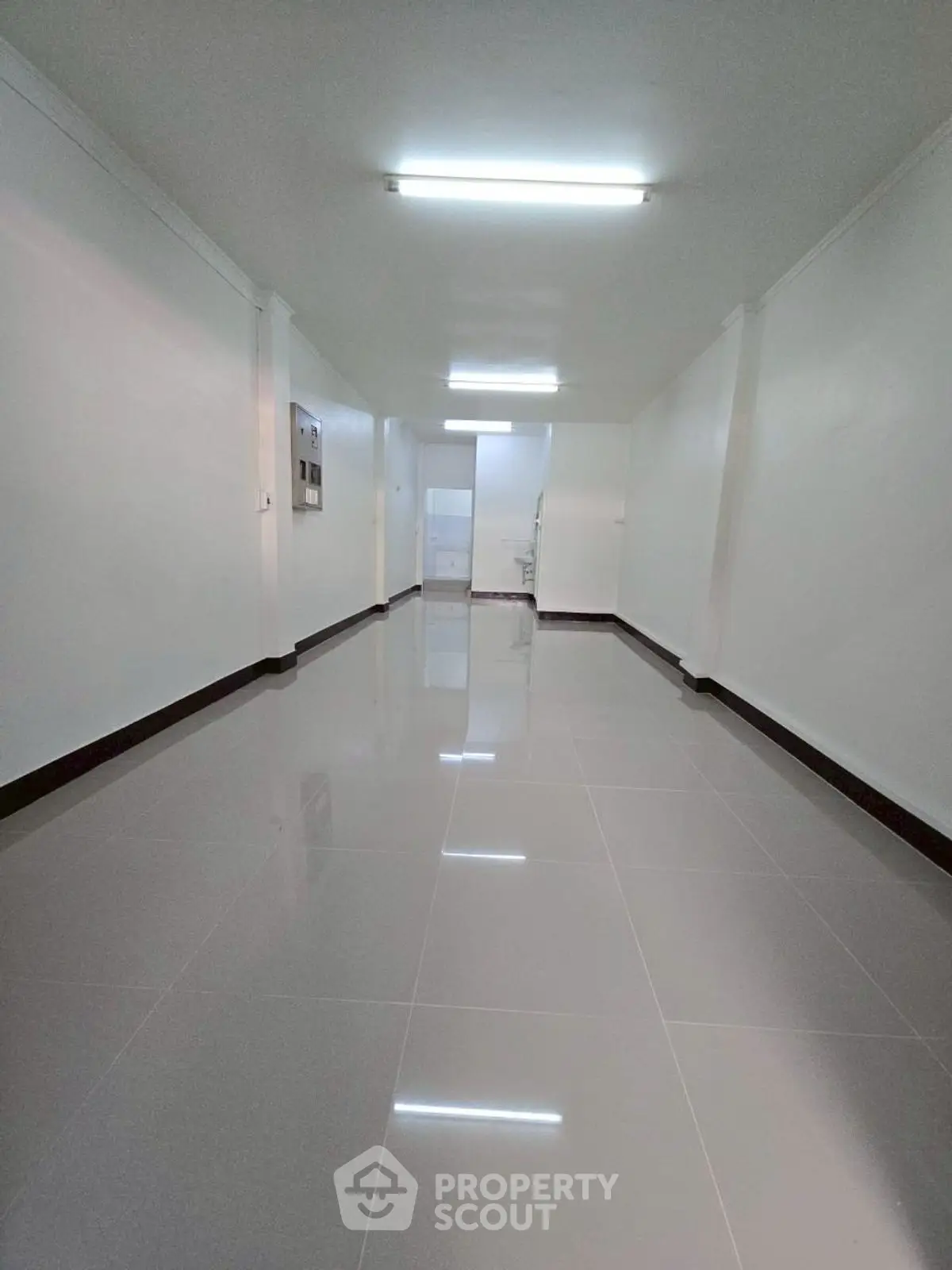 Spacious empty hallway with glossy tiled flooring and bright lighting.