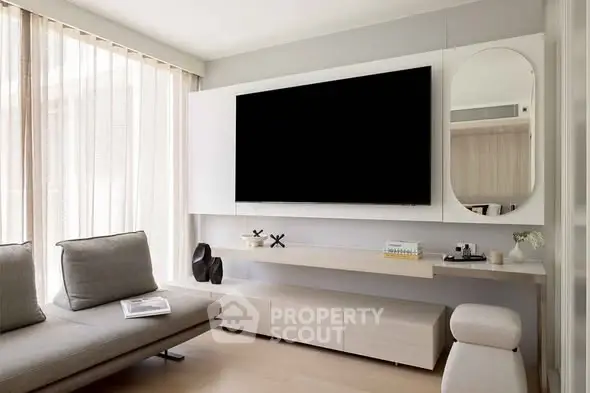 Modern living room with sleek furniture and large TV, featuring minimalist design and natural light.
