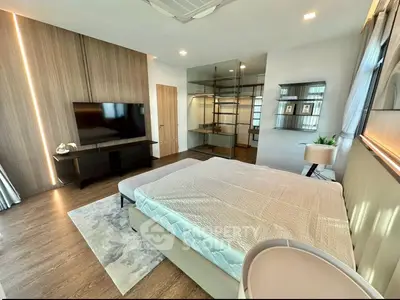 Spacious modern bedroom with stylish decor and large TV