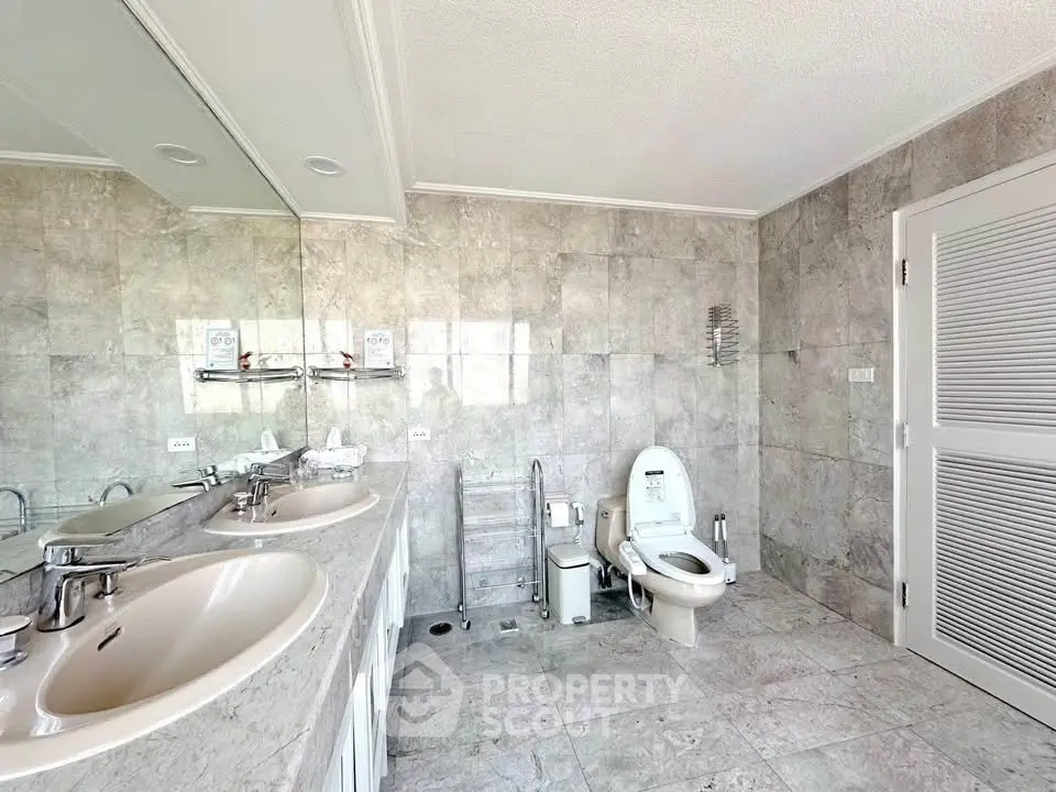 Spacious modern bathroom with dual sinks and elegant stone tiles