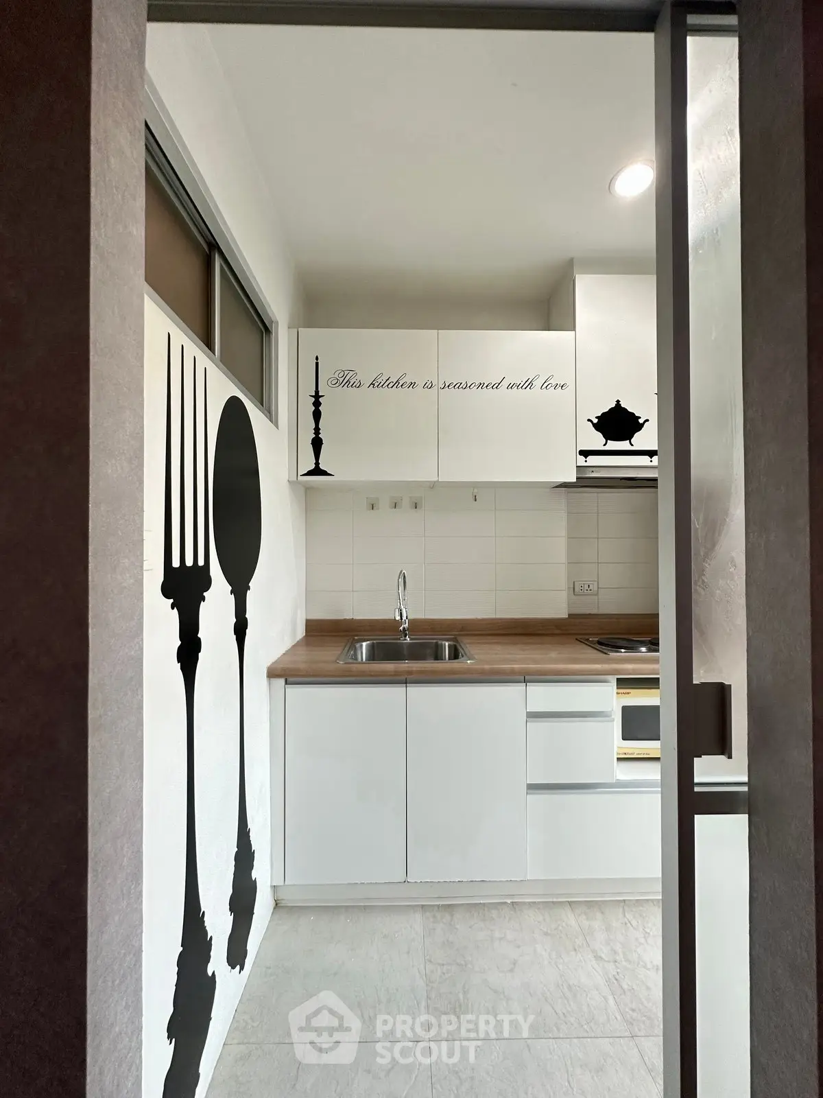 Modern kitchen with white cabinets and decorative wall art, featuring a sleek open layout and contemporary design.