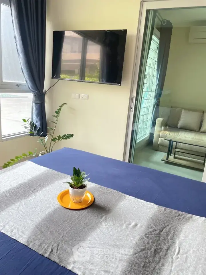 Modern bedroom with TV and balcony access, featuring stylish decor and natural light.