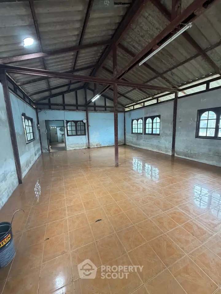 Spacious industrial-style room with tiled flooring and large windows, perfect for creative workspace or storage.