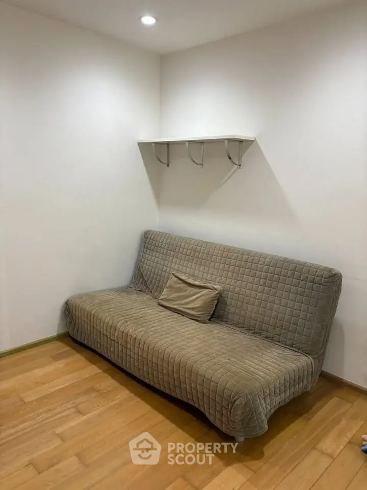 Cozy living room corner with a comfortable sofa and wooden flooring, perfect for relaxation.