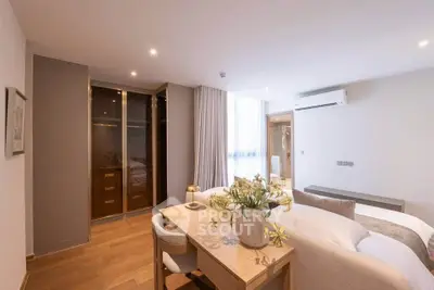 Modern bedroom with elegant decor and natural light, featuring a cozy workspace and stylish furnishings.